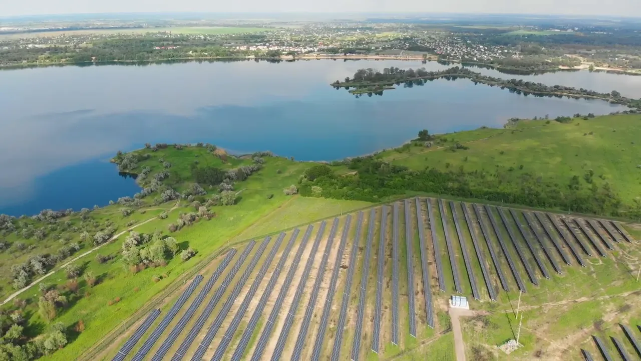 Rows of solar panels in a field beside a lake