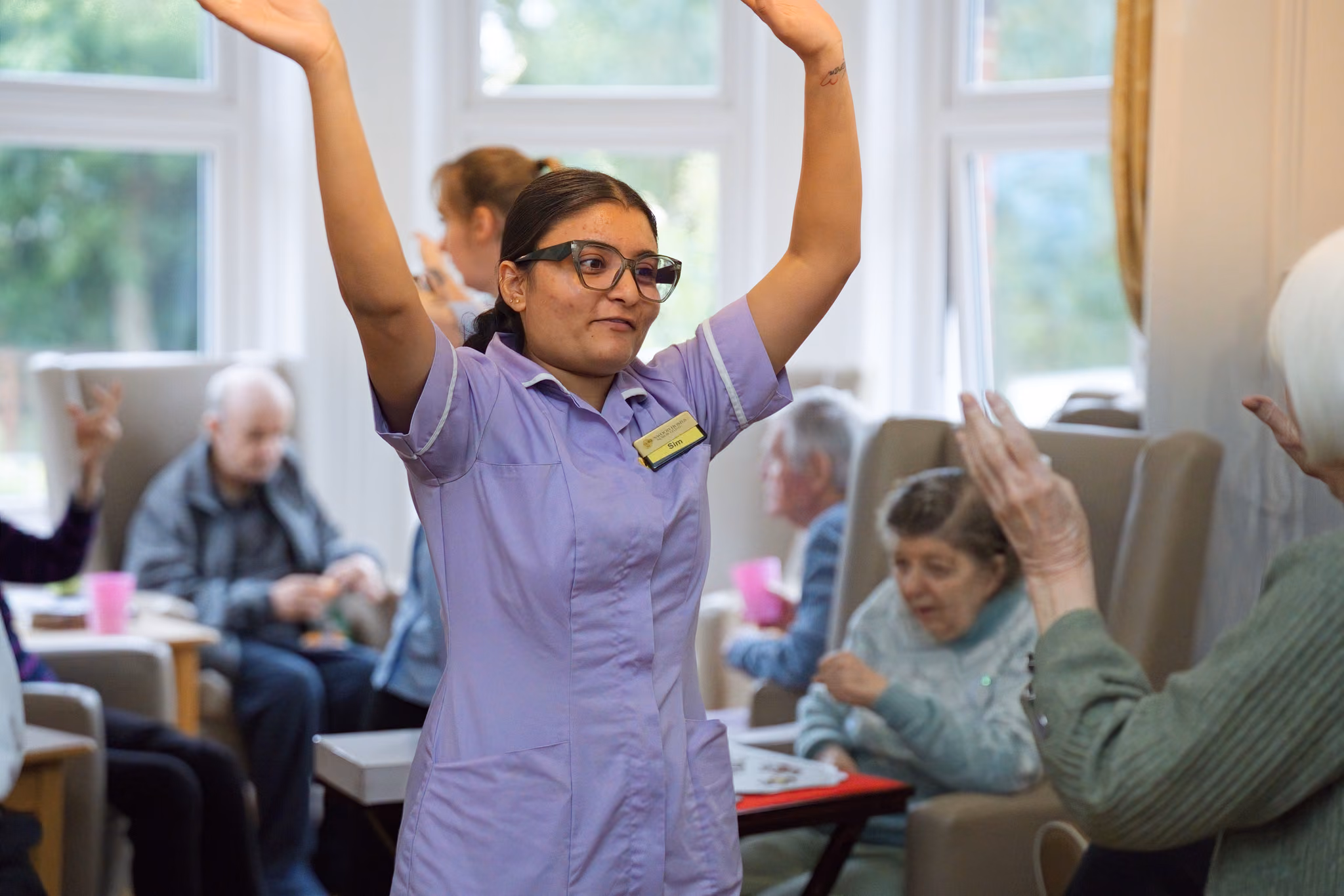 A member of the care team raising her arms during a group activity