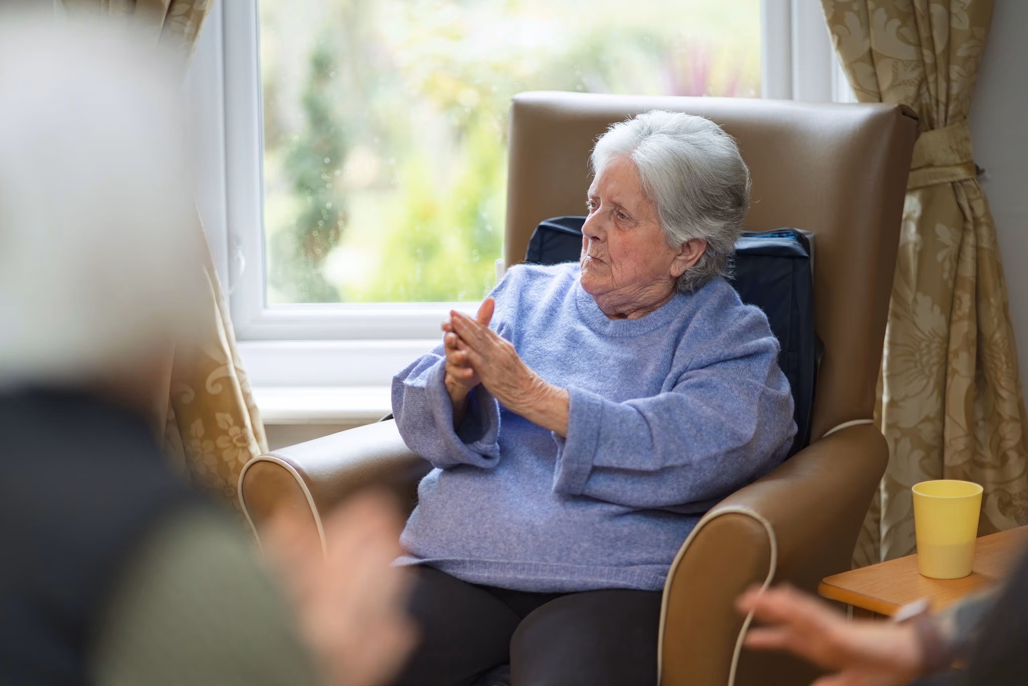 A resident clapping beside a living-room window