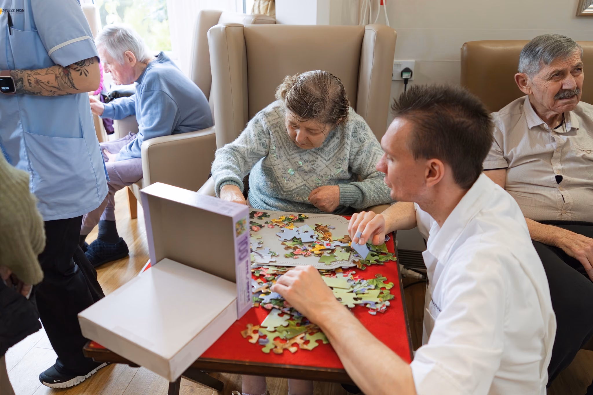 A staff member joining a resident at a jigsaw puzzle