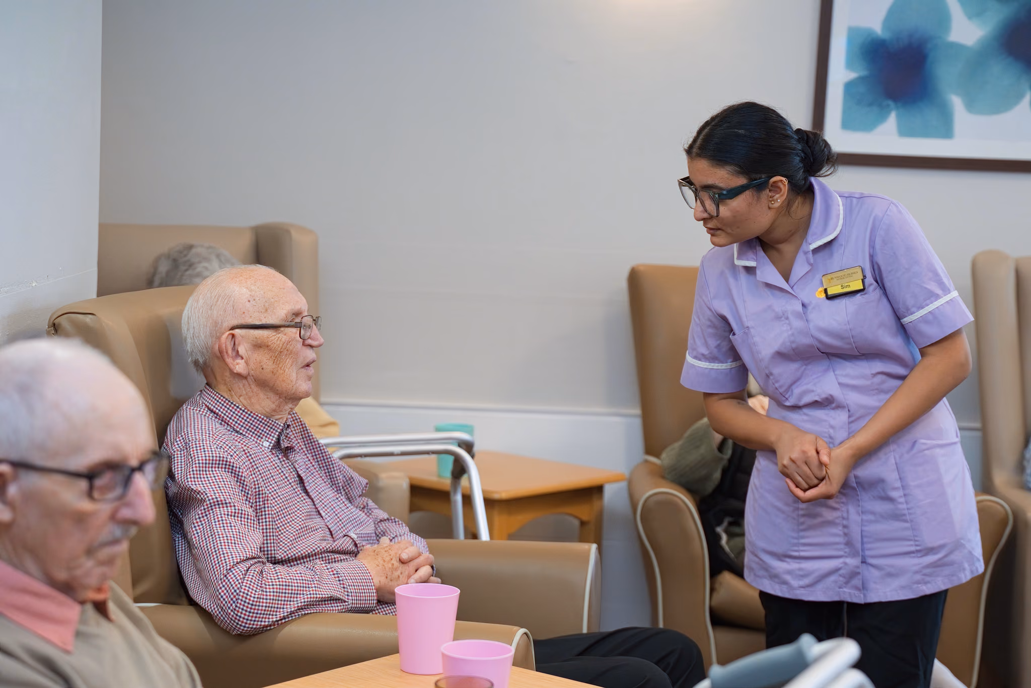 A carer chatting with a resident beside his armchair