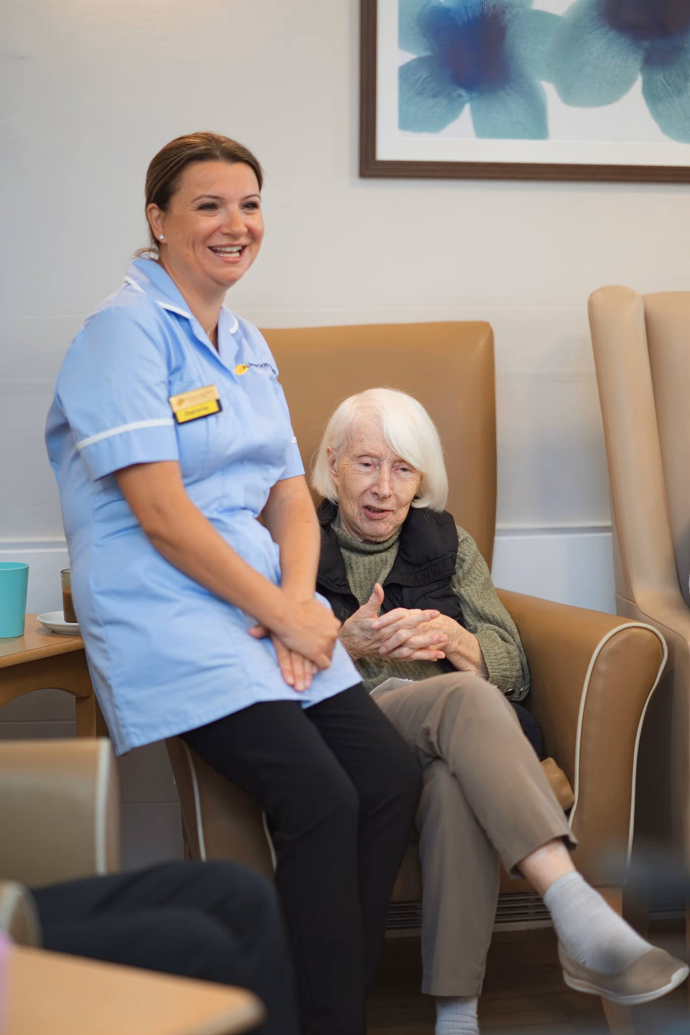 A carer sitting beside a smiling resident