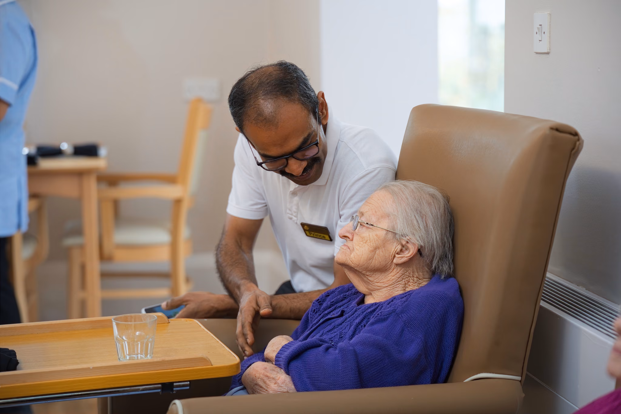 A staff member holding a resident’s hand during a conversation