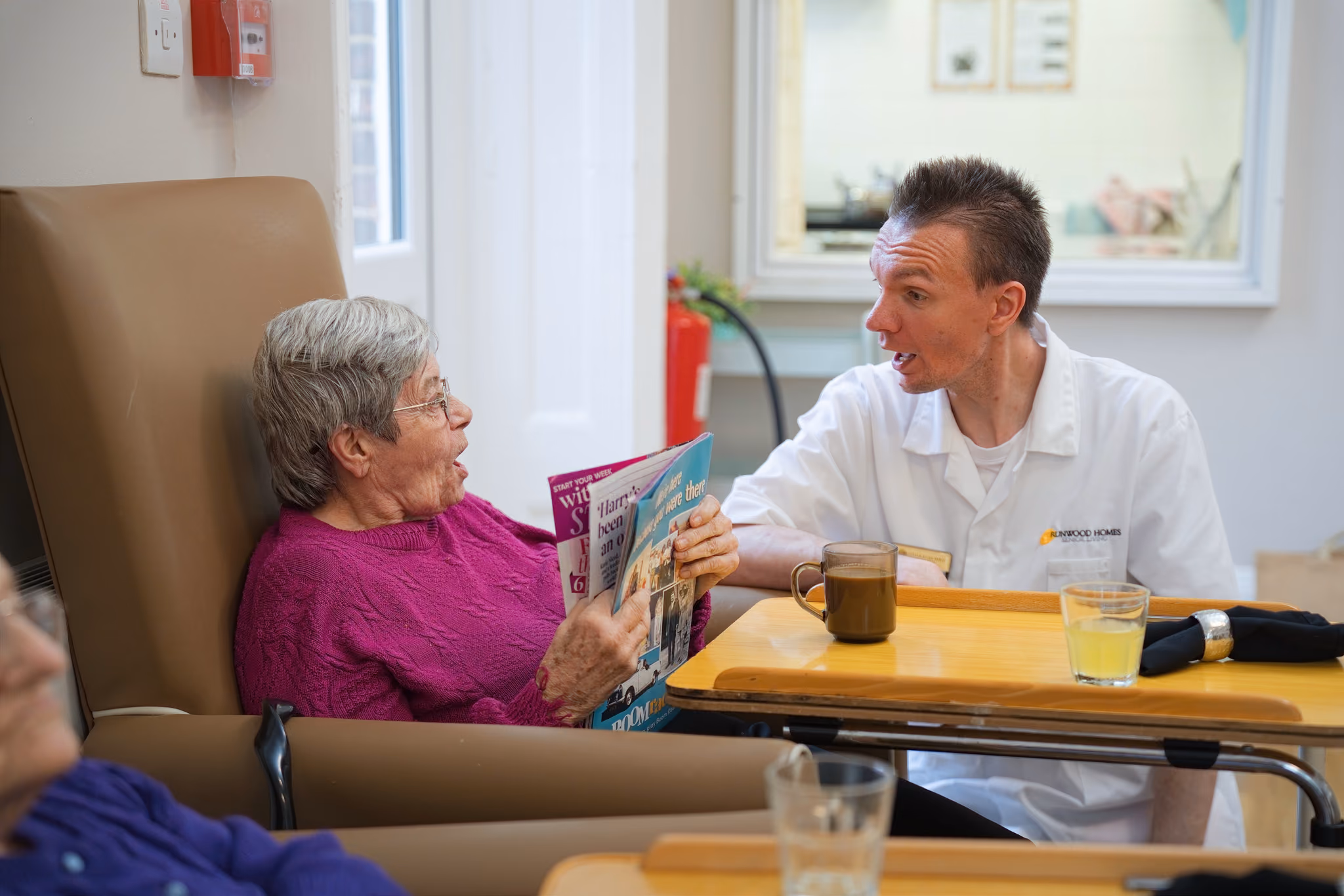 A resident and staff member smiling while looking at a book