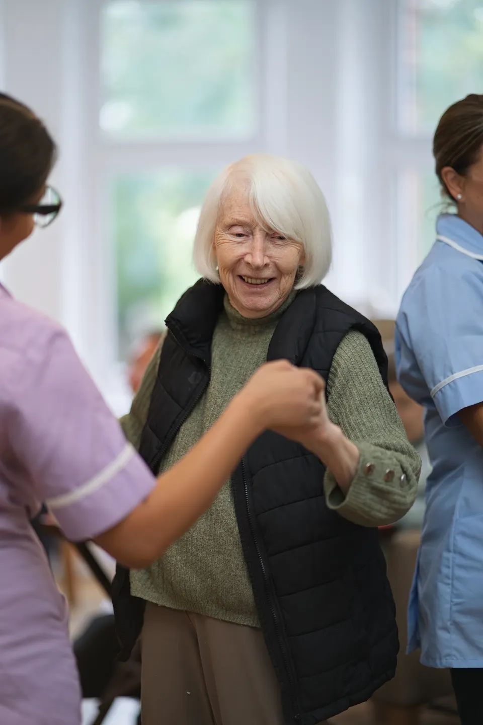A resident smiling while dancing with a carer