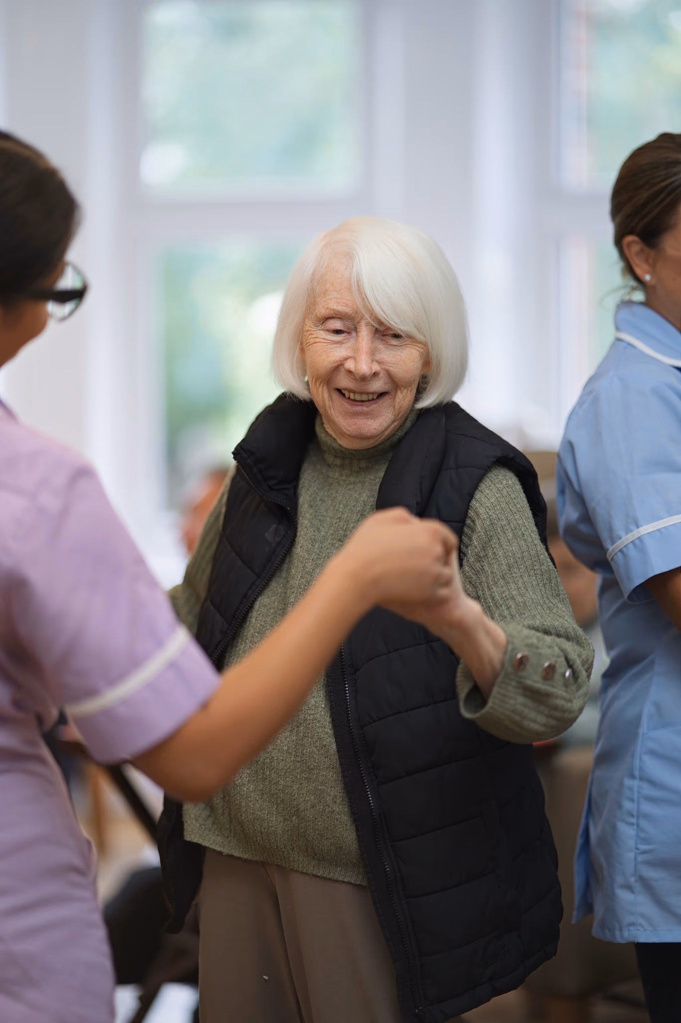 A resident smiling while dancing with a carer
