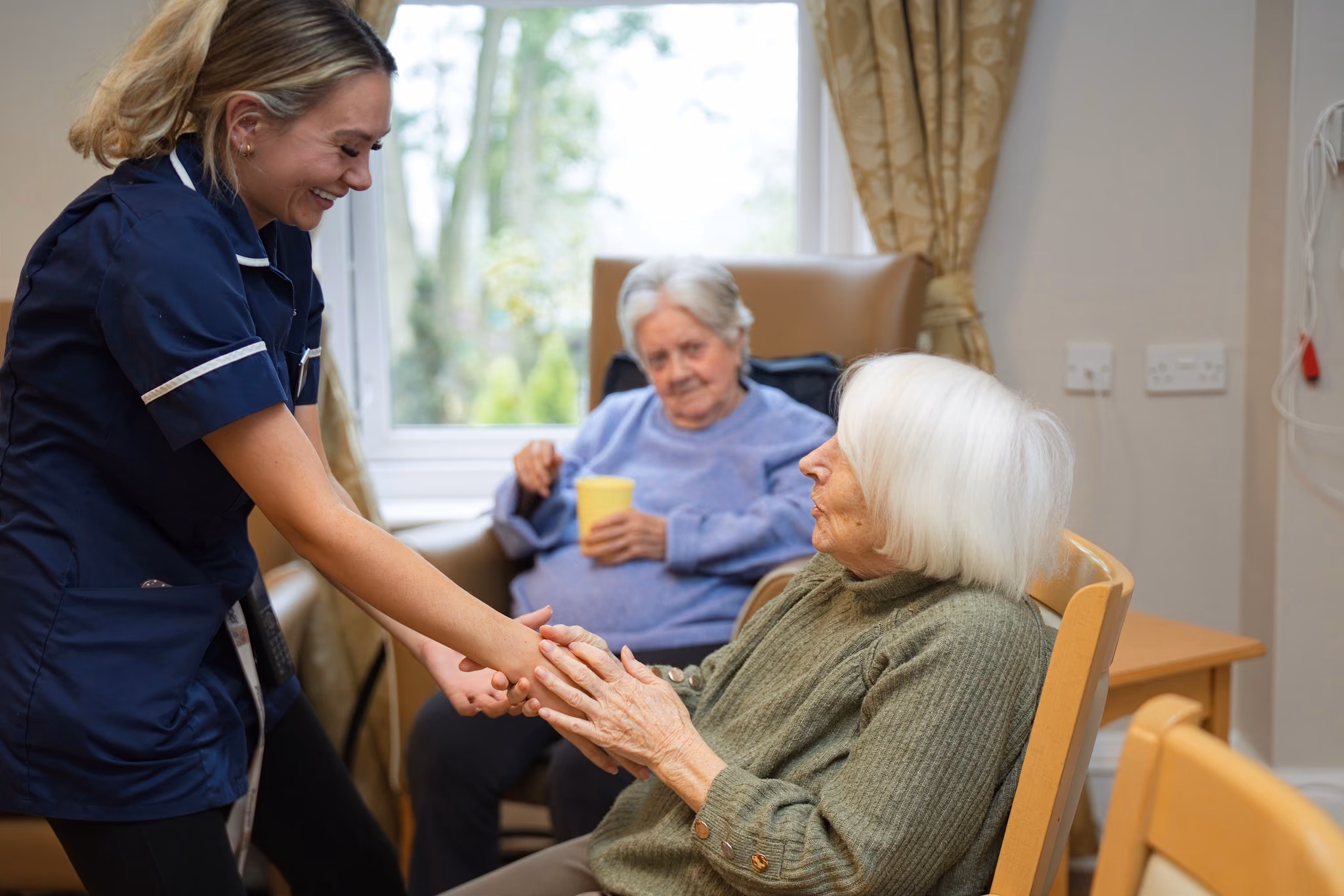 A carer holding a resident’s hands between activities