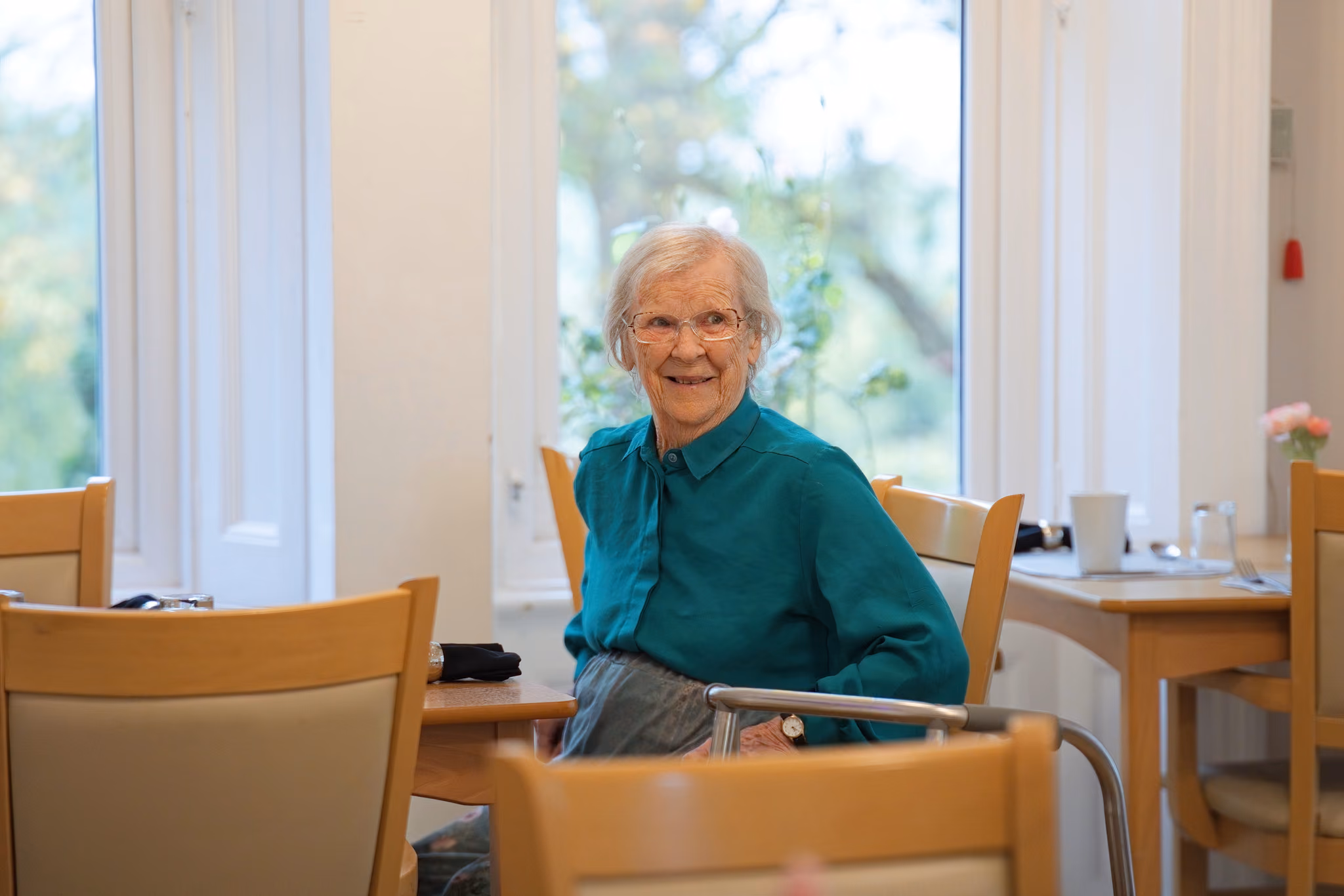 A resident smiling beside a living-room window