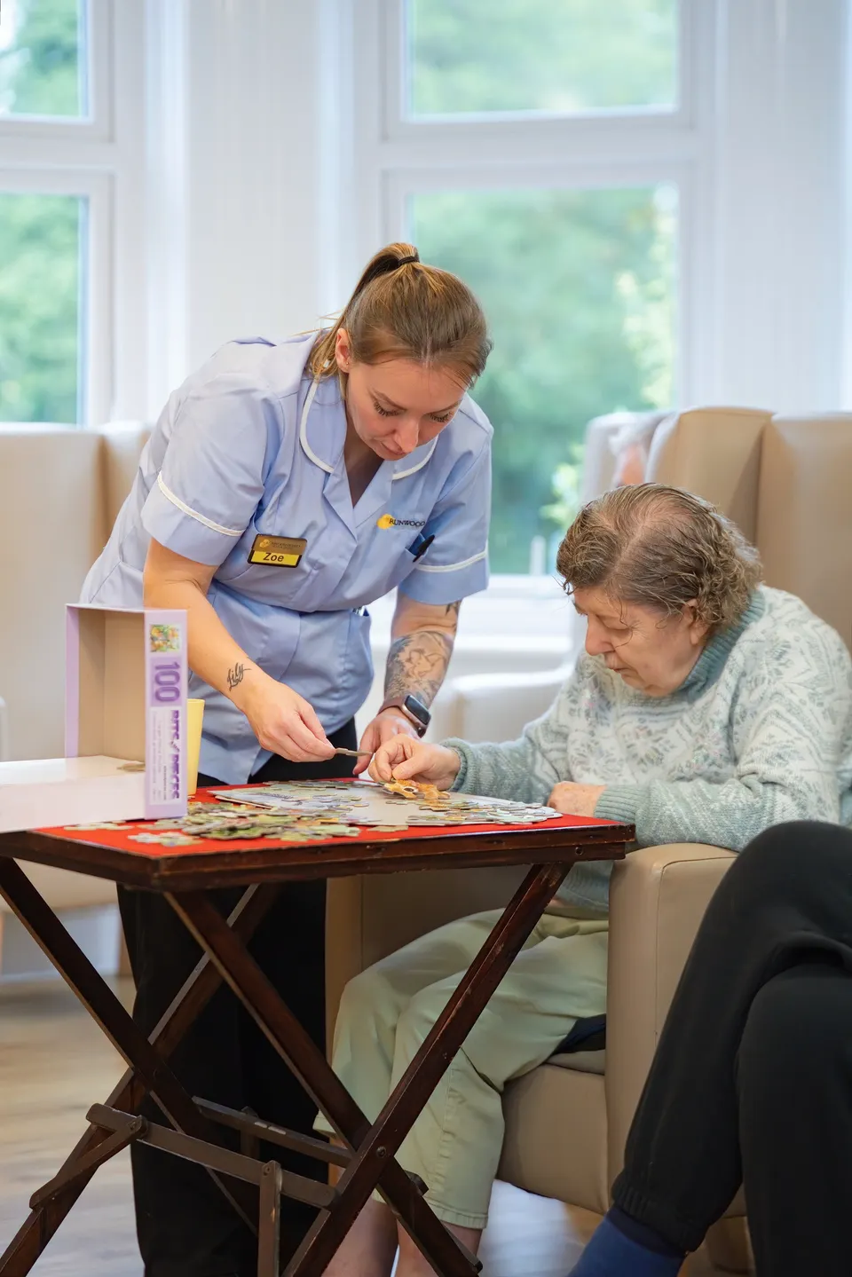 A carer working on a jigsaw puzzle with a resident