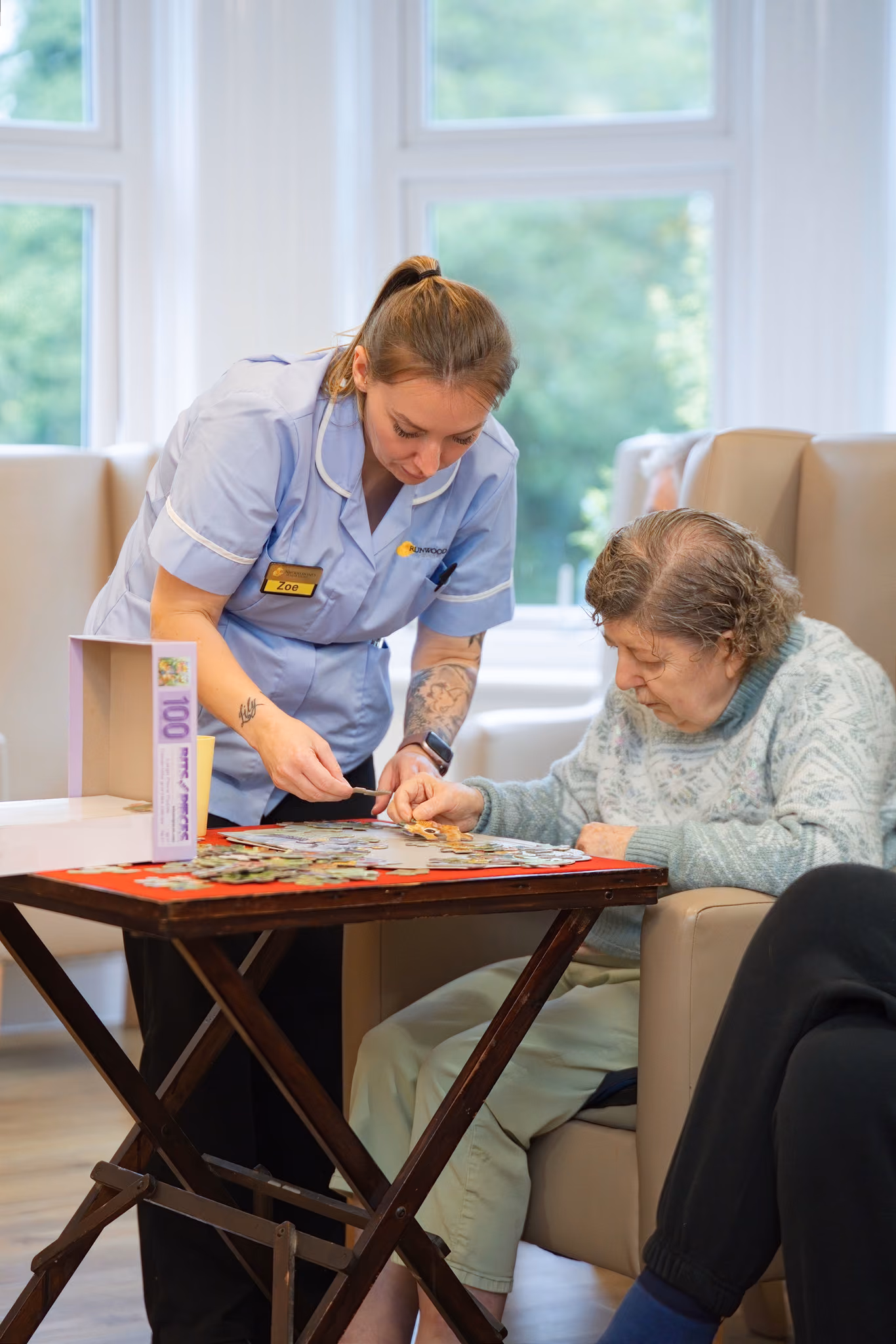 A carer working on a jigsaw puzzle with a resident