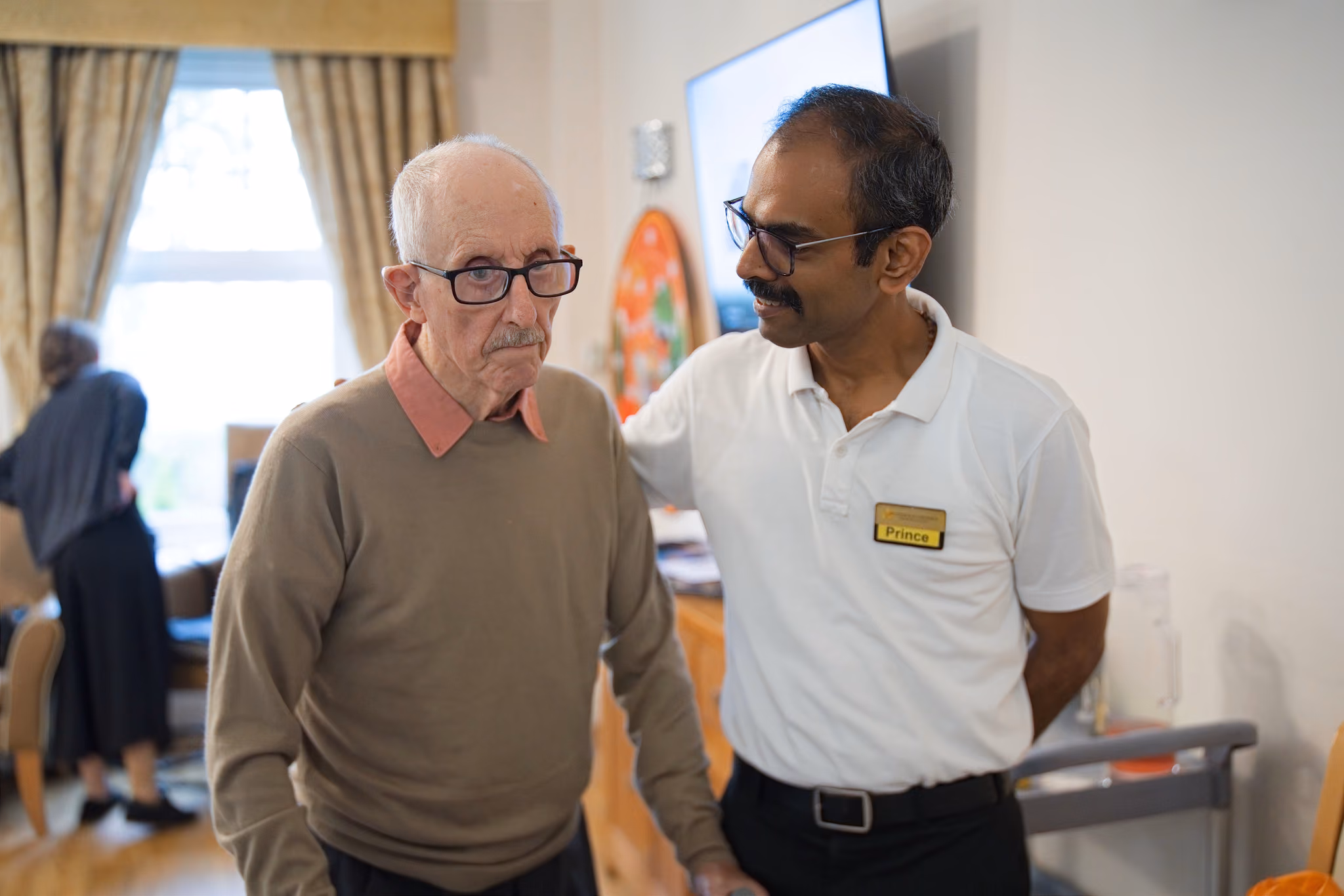 A member of staff beside a resident in the dining room