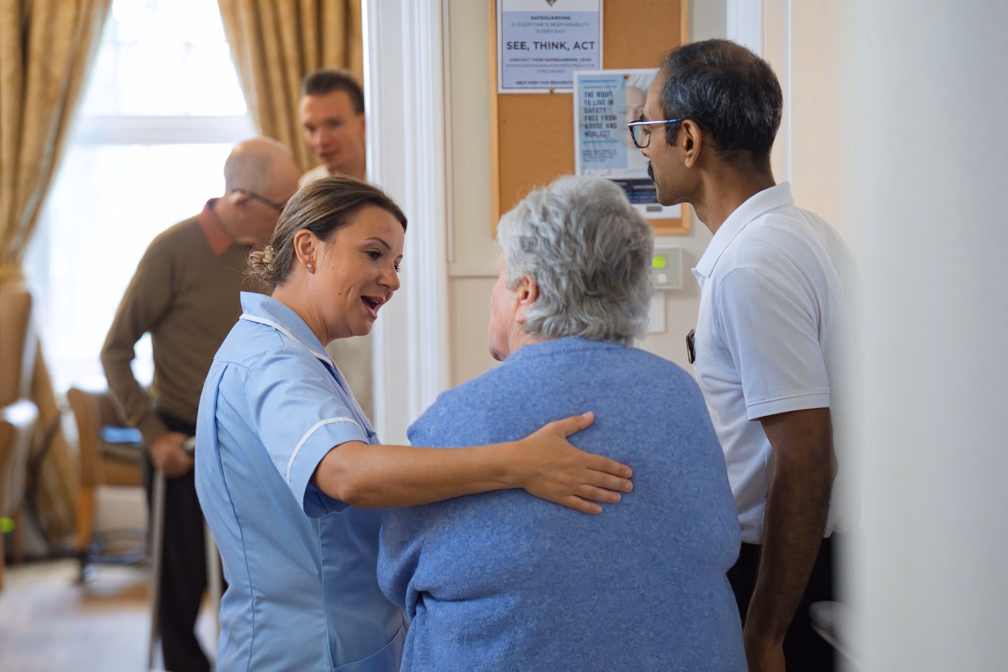 A carer with her arm around a resident in a doorway