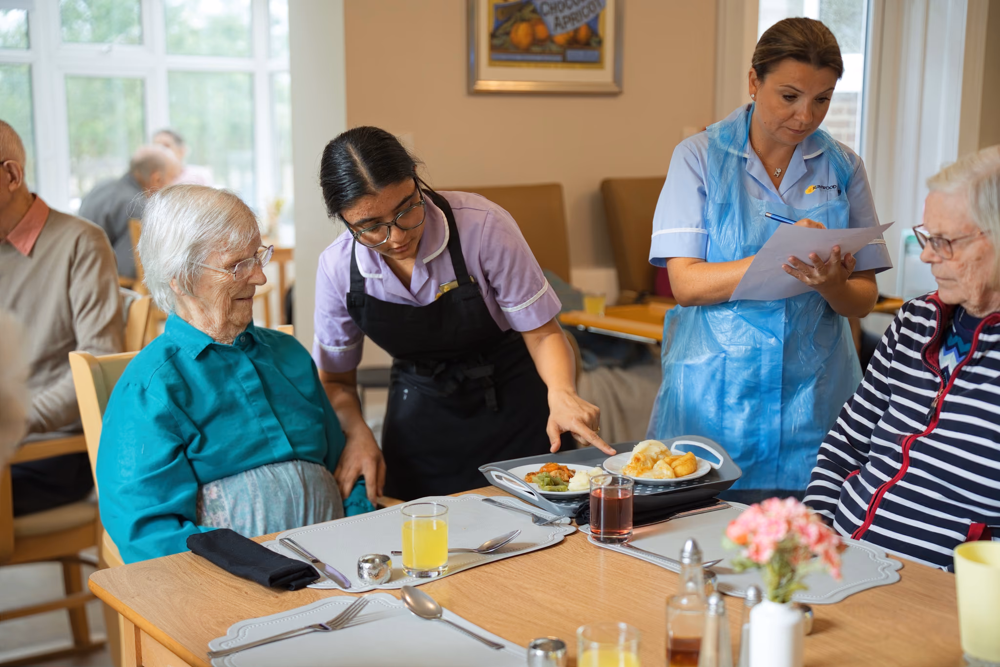 Care staff serving residents at the dining table