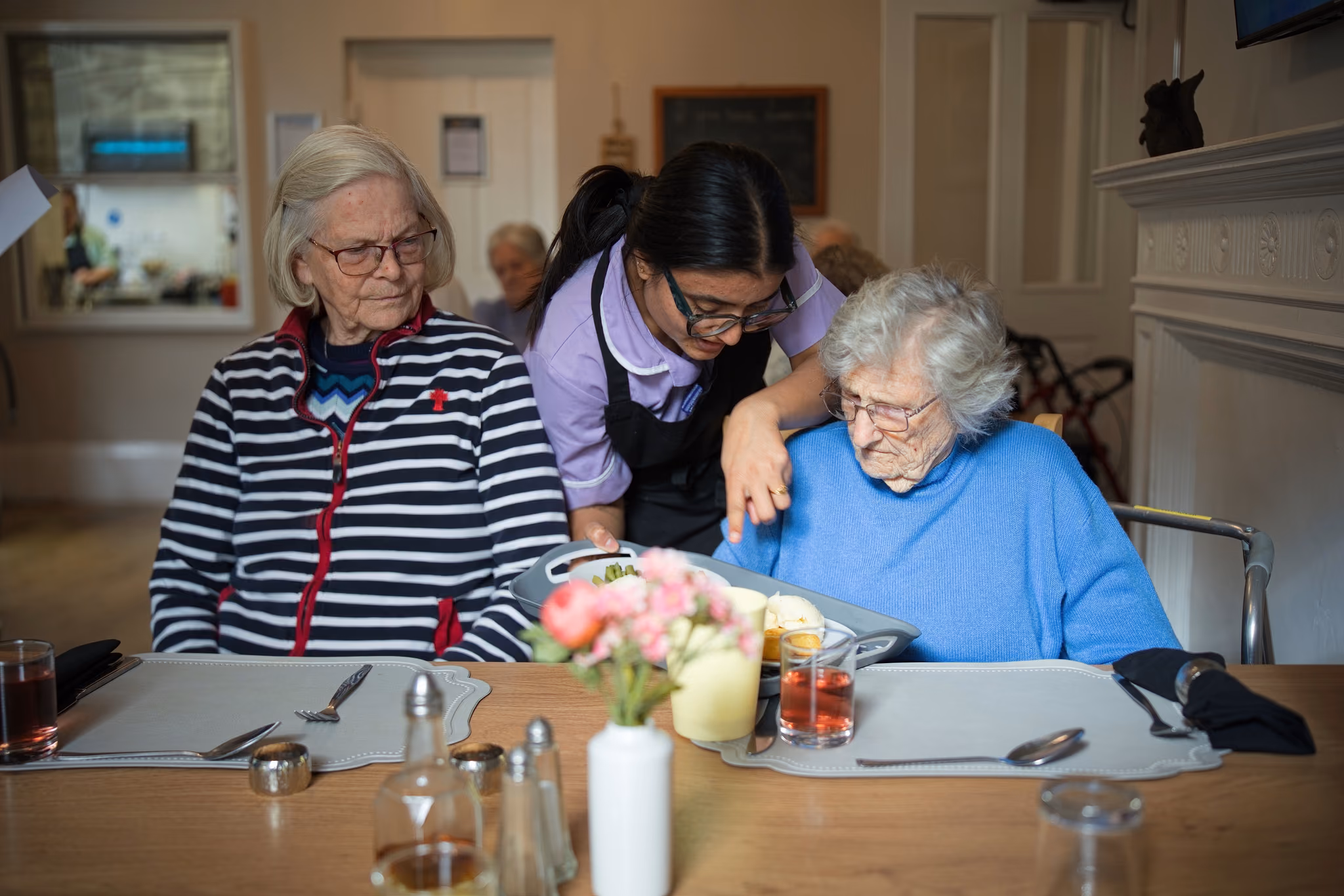A carer embracing a resident at the dining table