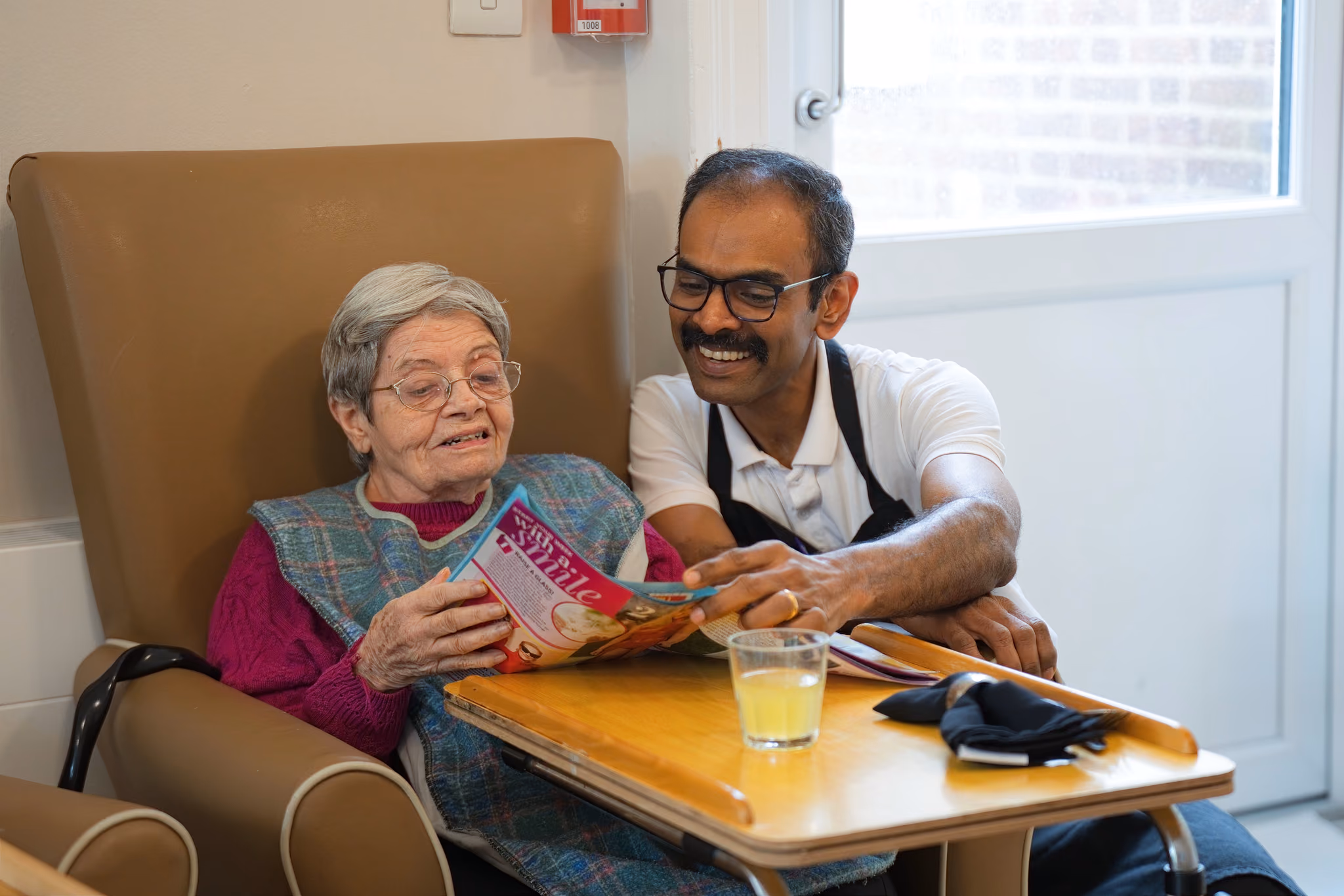 A staff member reading a book with a resident