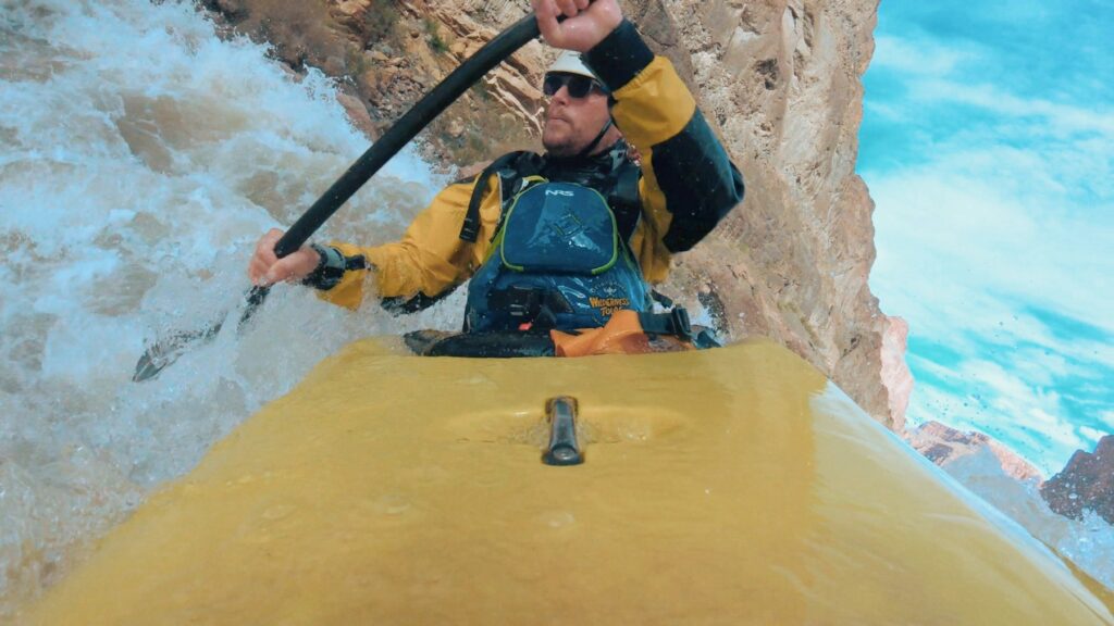 A kayaker in white water filmed from an action camera mounted on the boat