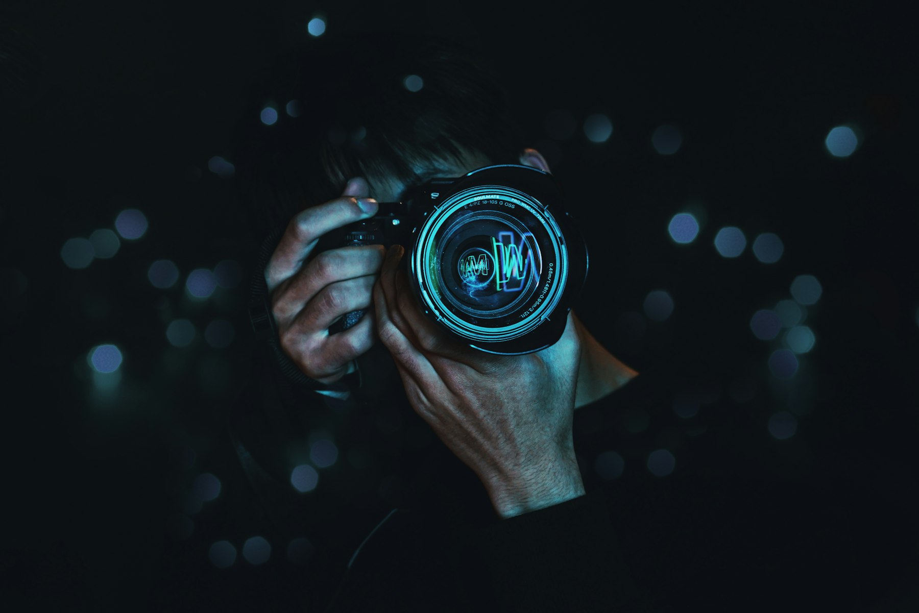 A photographer holding a camera up to the eye at night