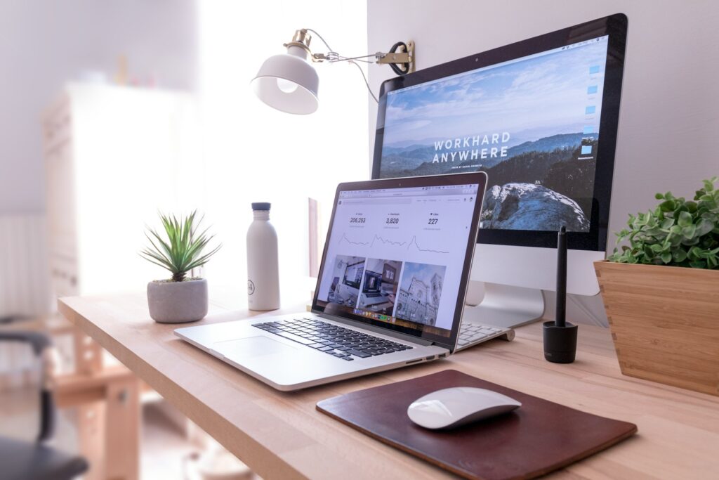 A tidy desk with a laptop and monitor showing a website