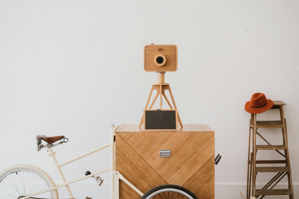 A wooden photo booth with a camera on a tripod set up for an event