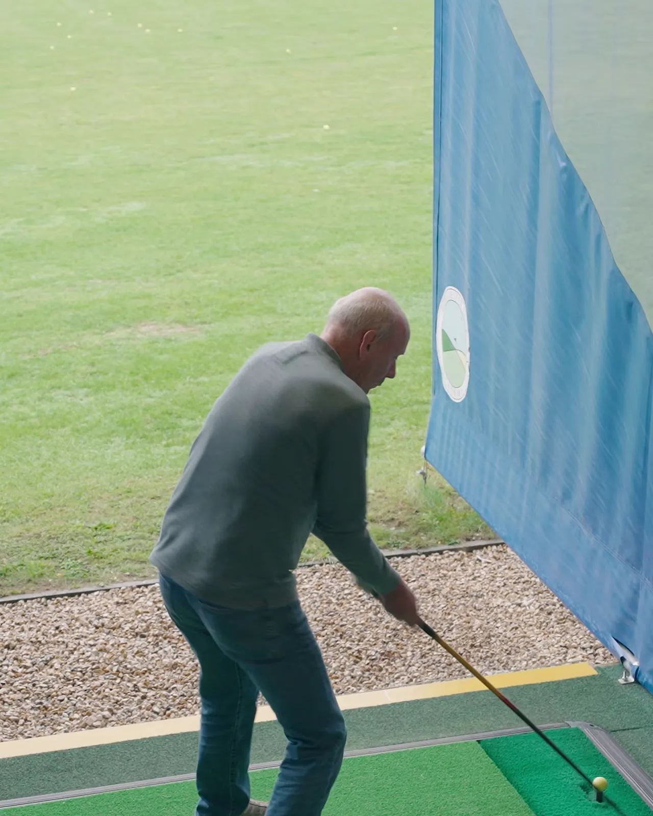 Golfer practising in a driving bay