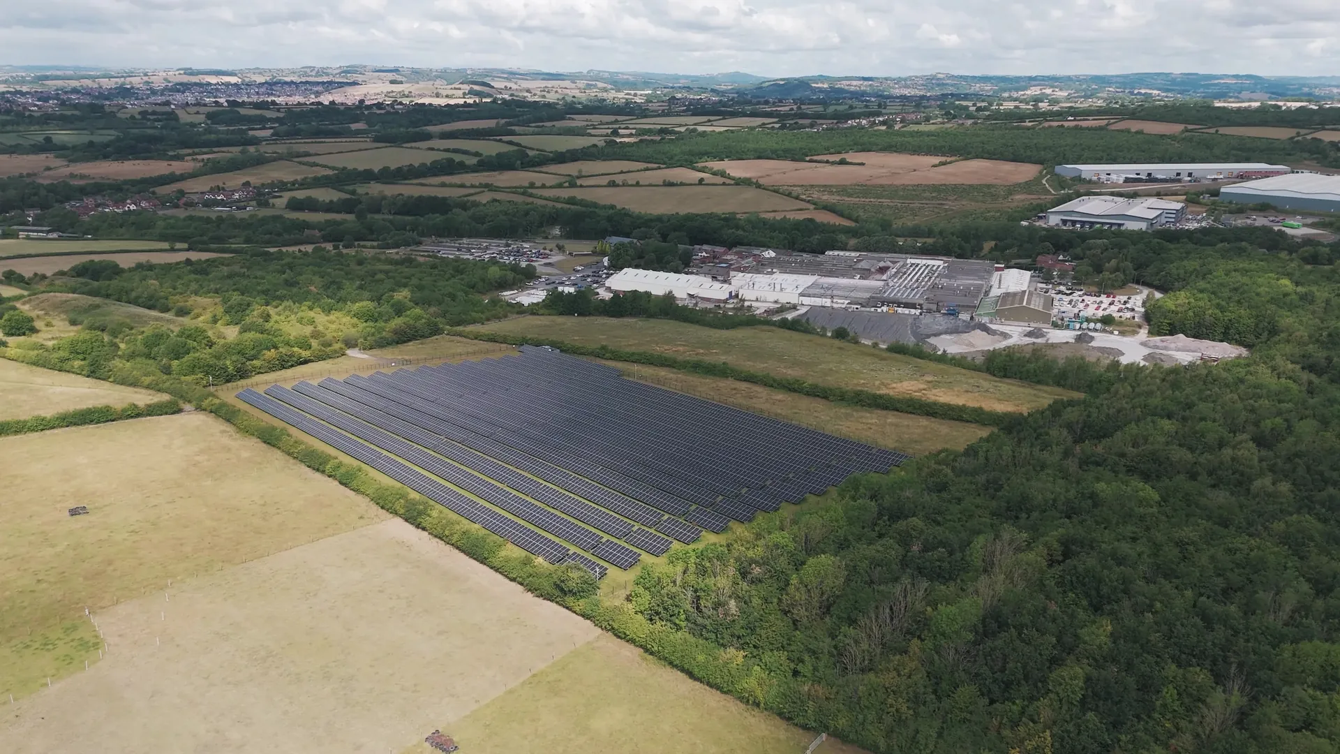 Aerial view of a solar array beside a factory