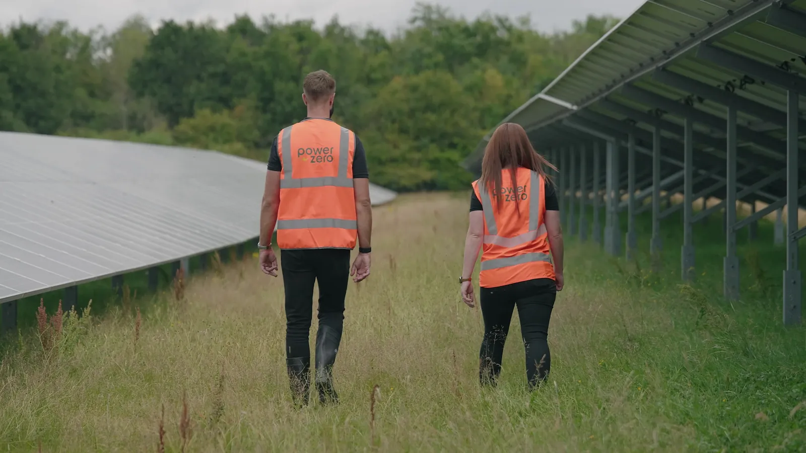 Two people walking between solar panels