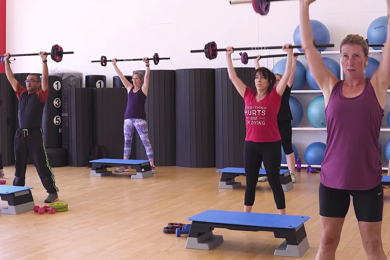 Instructor leading a barbell pump class