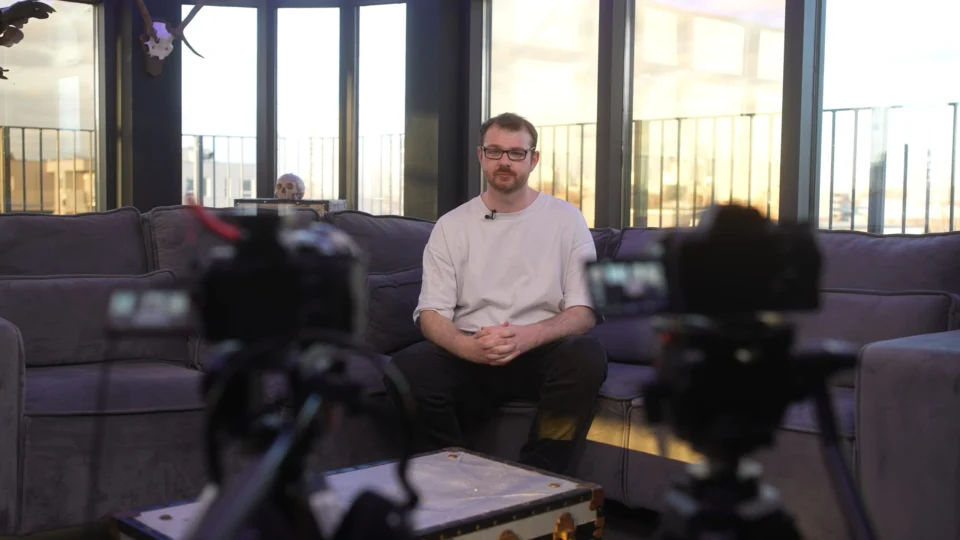 Two cameras set up on a seated presenter in a lounge studio