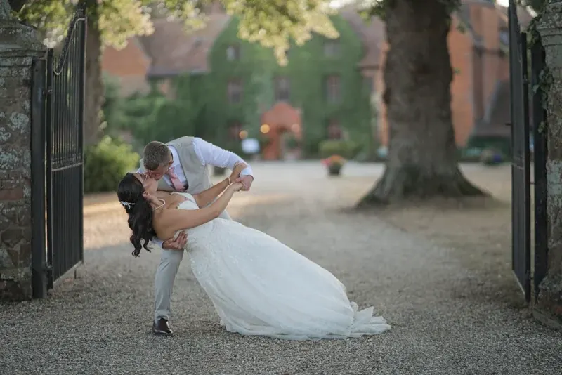 Kieran dipping Androulla for a kiss on a tree-lined drive