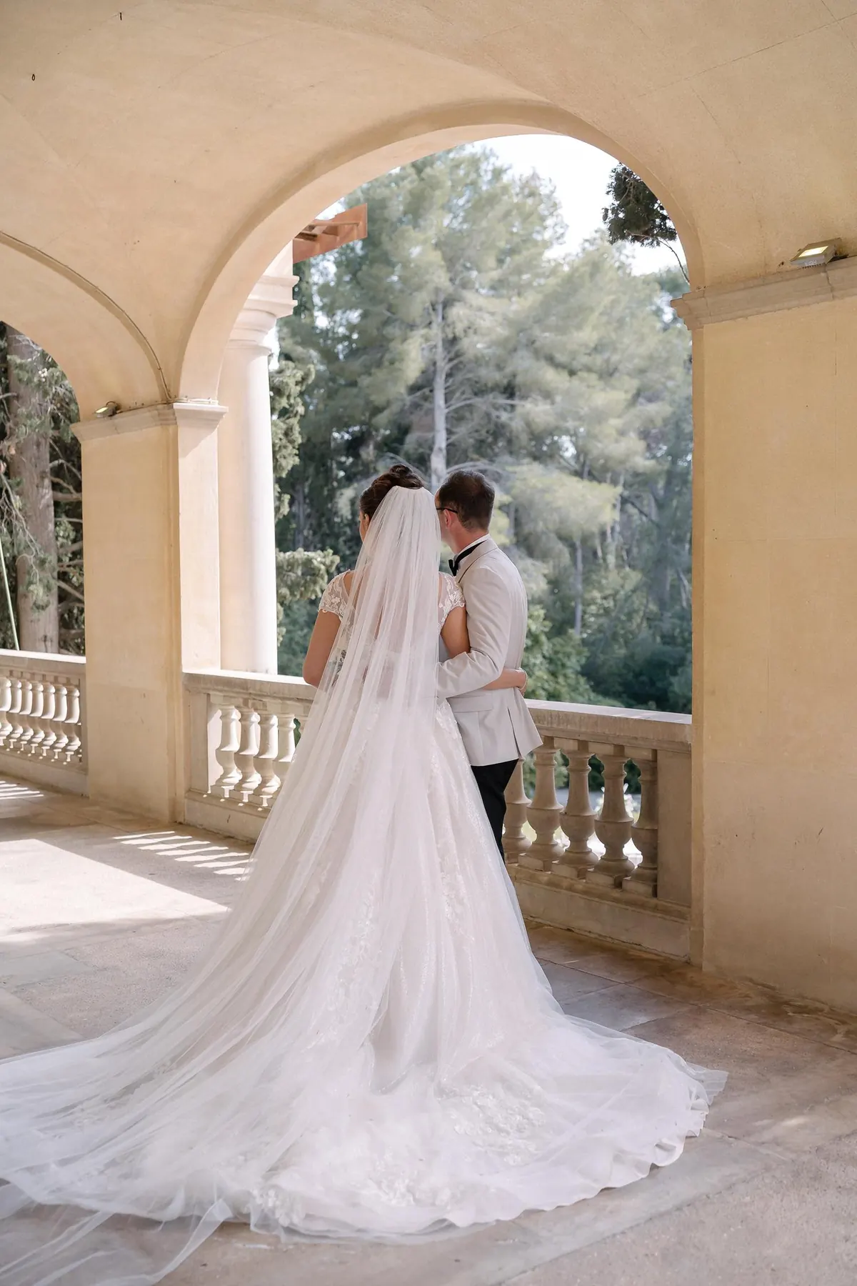 Ellie and Ernie under a sunlit archway, her veil trailing across the floor