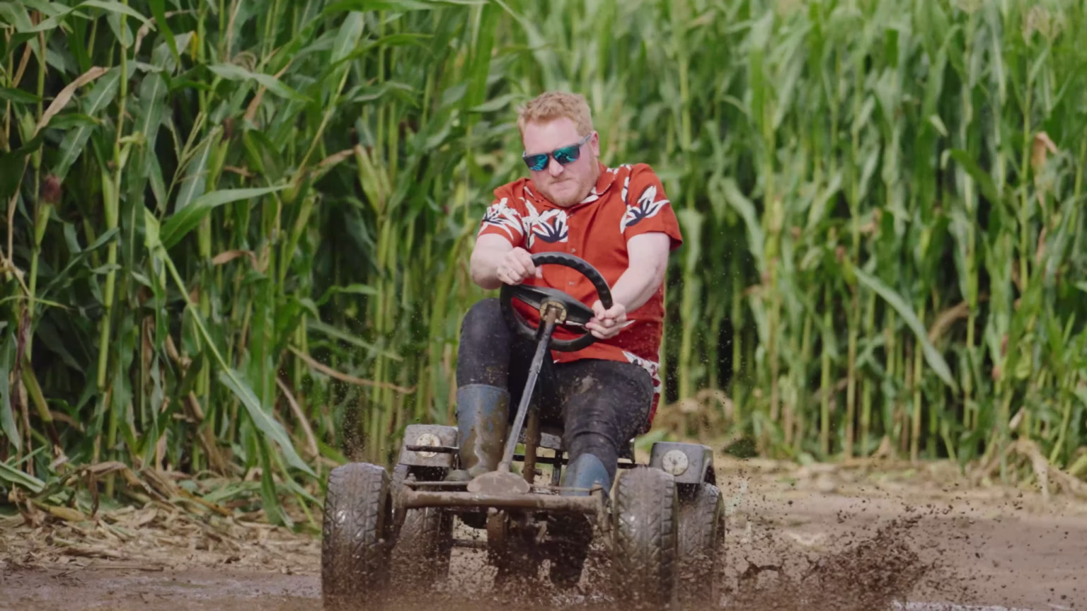 Visitor driving a pedal go-kart beside the maize at Southwold Maize Maze