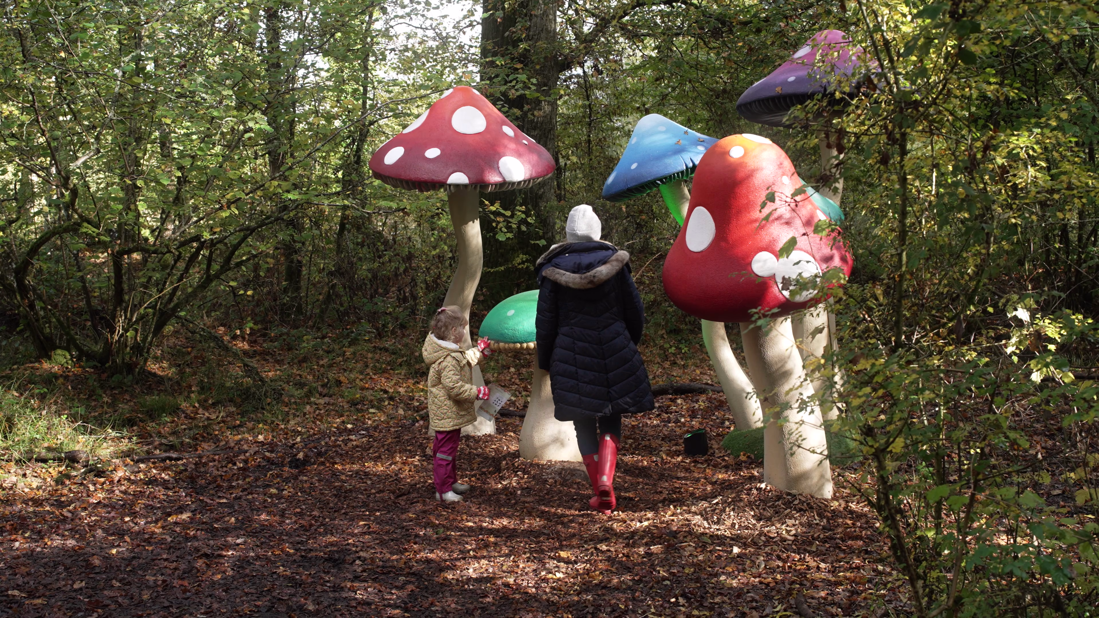 Family exploring the giant mushroom installation on Wasing Estate woodland trail